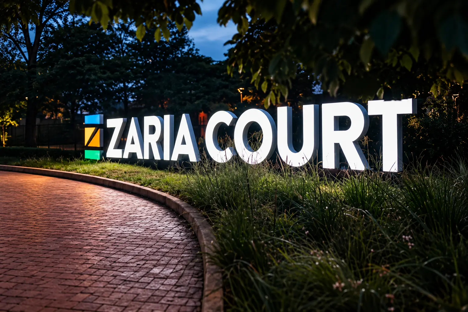 Zaria Court illuminated entrance monument identity at night